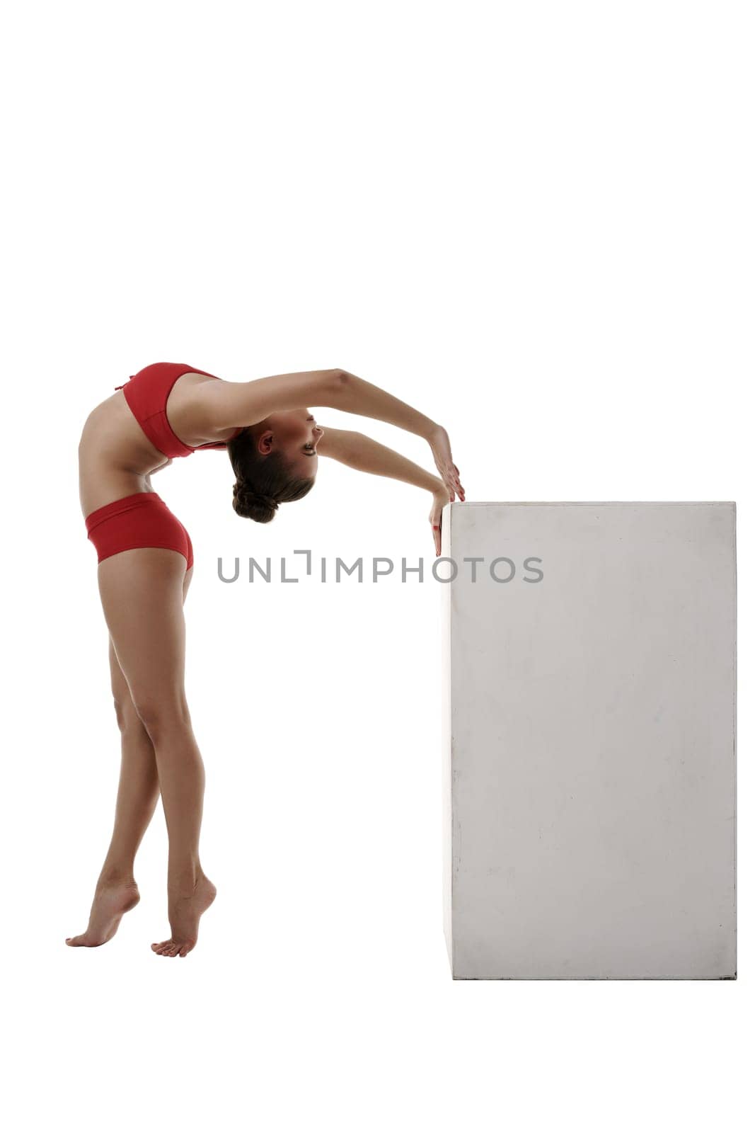 Image of flexible gymnast arched her back to cube. Isolated on white