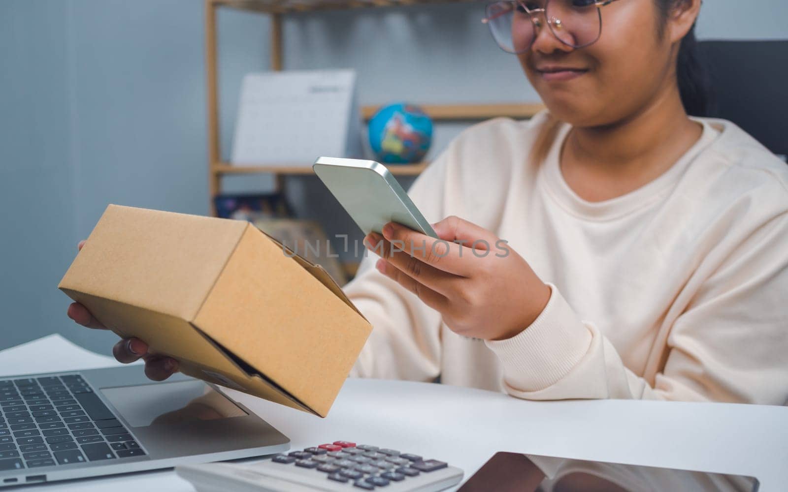 Woman runs an e-commerce business is checking orders from laptop, she owns an online store, she packs and ships through a private transport company. Online selling and online shopping concepts.