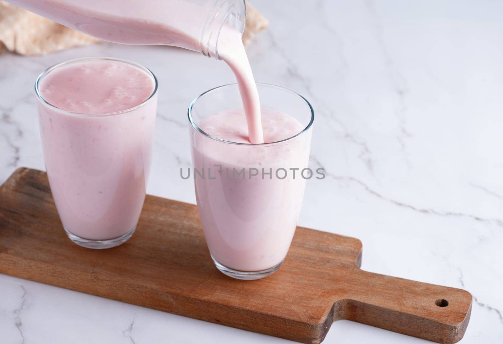 Pouring homemade fruit kefir, buttermilk or yogurt with probiotics. by NataliPopova