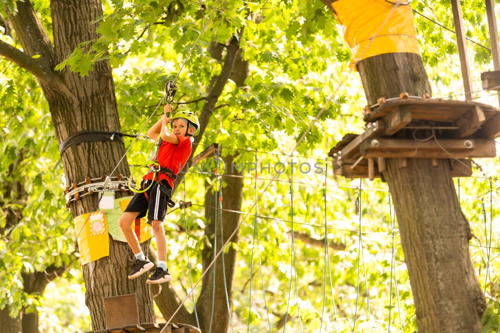 Adorable little girl enjoying her time in climbing adventure park on warm and sunny summer day.