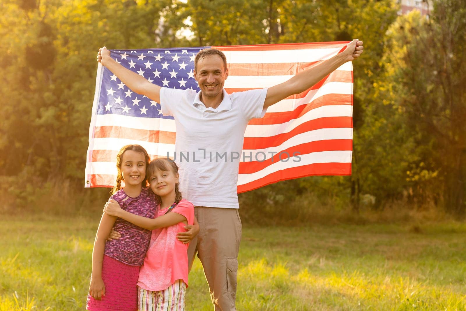 happy family with the flag of america USA at sunset outdoors by Andelov13