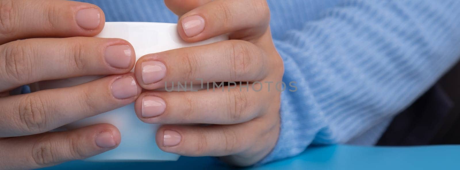 Stylish nude beige female nails on white cup. Modern trendy stylish Beautiful manicure. Cute pastel nail minimalistic design concept of beauty treatment. Gel nails. Skin care by anna_stasiia