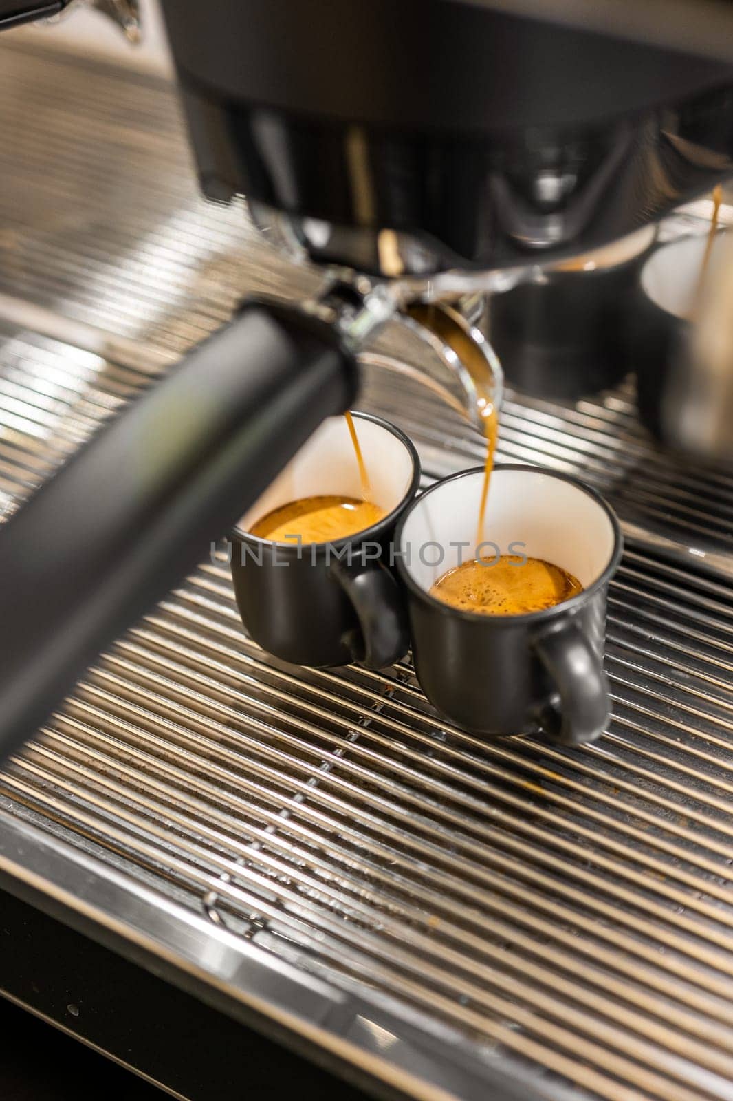 Espresso machine pouring fresh coffee into two black cups by apavlin