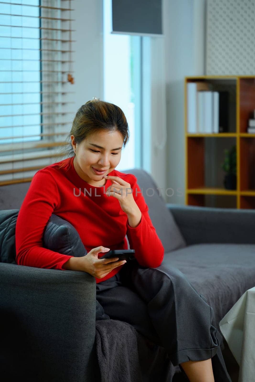 Portrait of young Asian woman checking social media or texting on mobile phone by prathanchorruangsak
