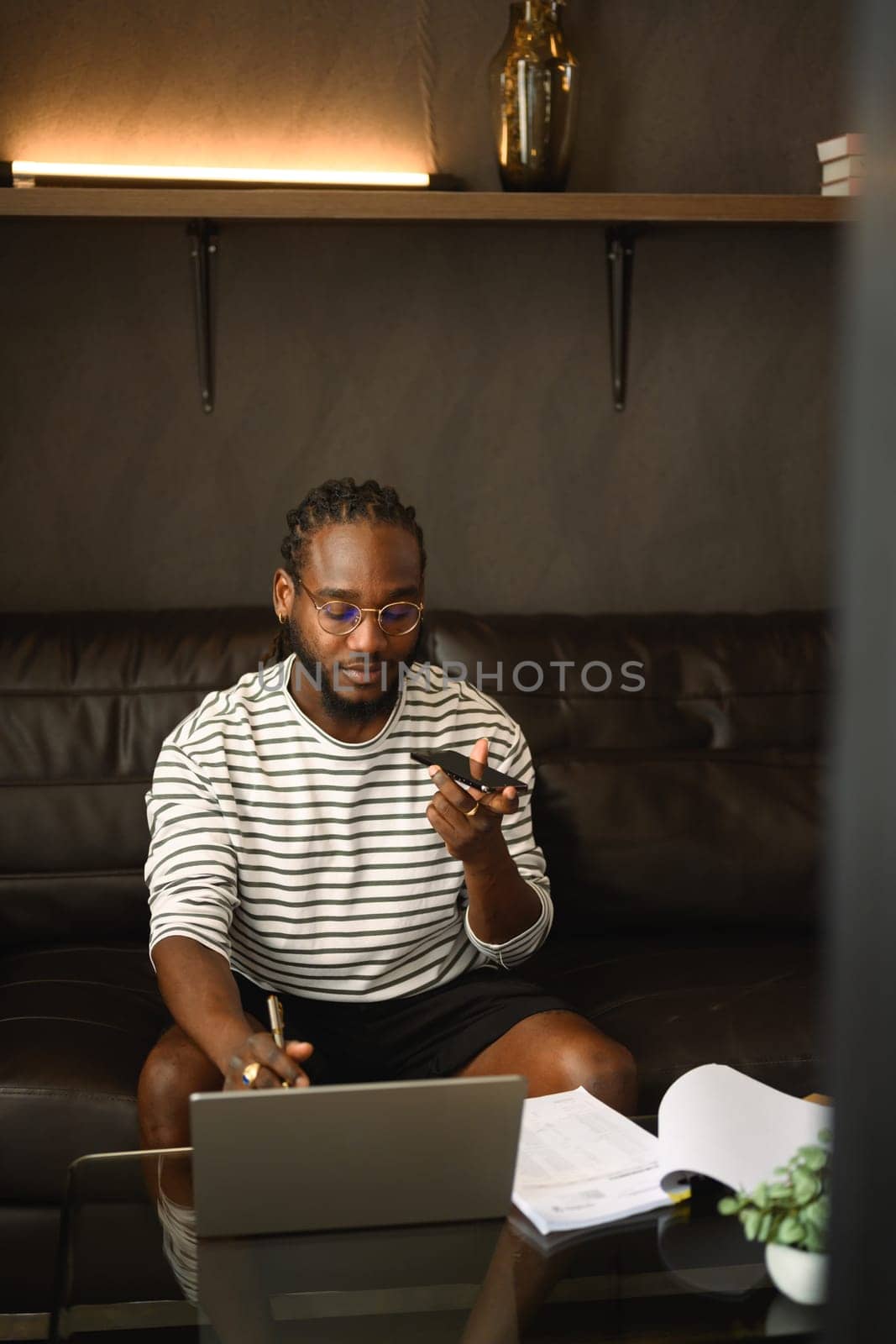 Millennial male freelancer working with laptop and talking on mobile phone at home.