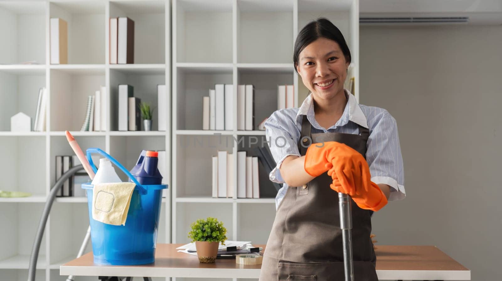 Young Asian housewife uses a vacuum cleaner to clean and vacuum the office..