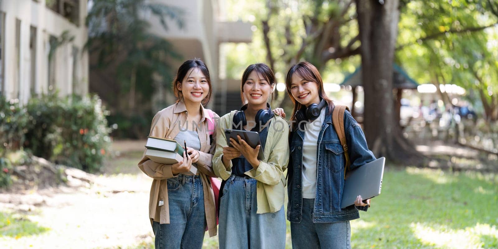 female student is walking to class with friends and stop to look at the camera. back to school concept by itchaznong