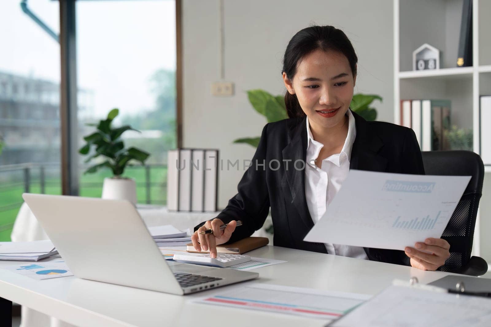 Businesswoman working with document and using calculator for checking finance report by itchaznong