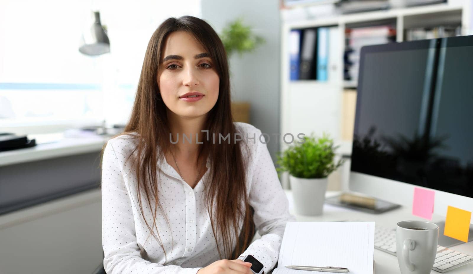 Pretty adult female sitting at worktable looking in camera headshot