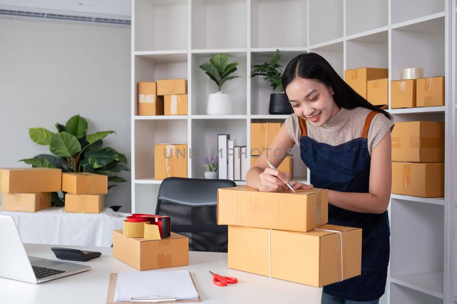 SME business entrepreneurs small in Asia Write shipping information on a cardboard box in home office. Small business operators preparing to ship to customer by wichayada