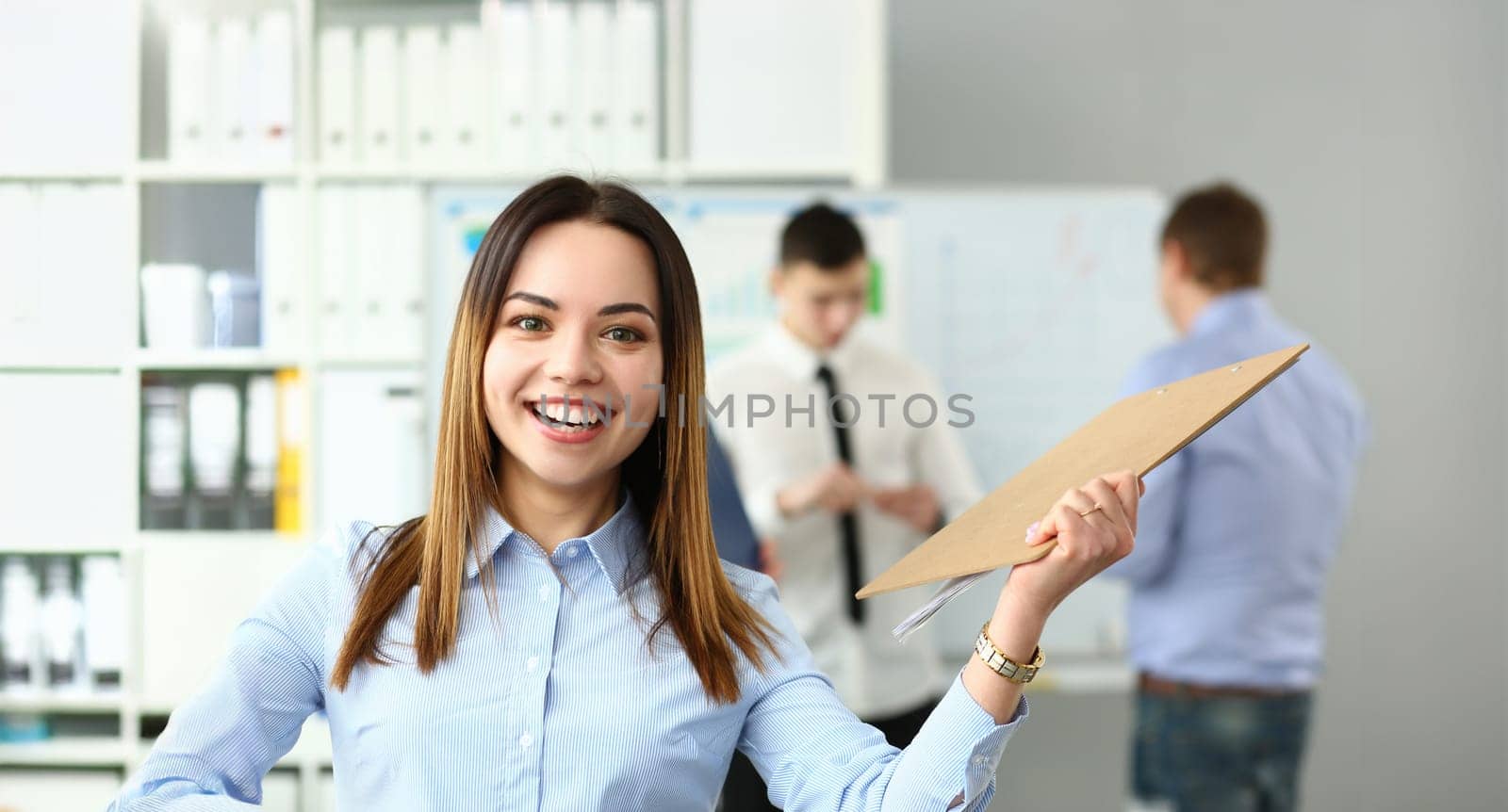 Portrait of happy woman working with smart colleagues in big modern building and participating in intense brainstorming process. Company meeting concept