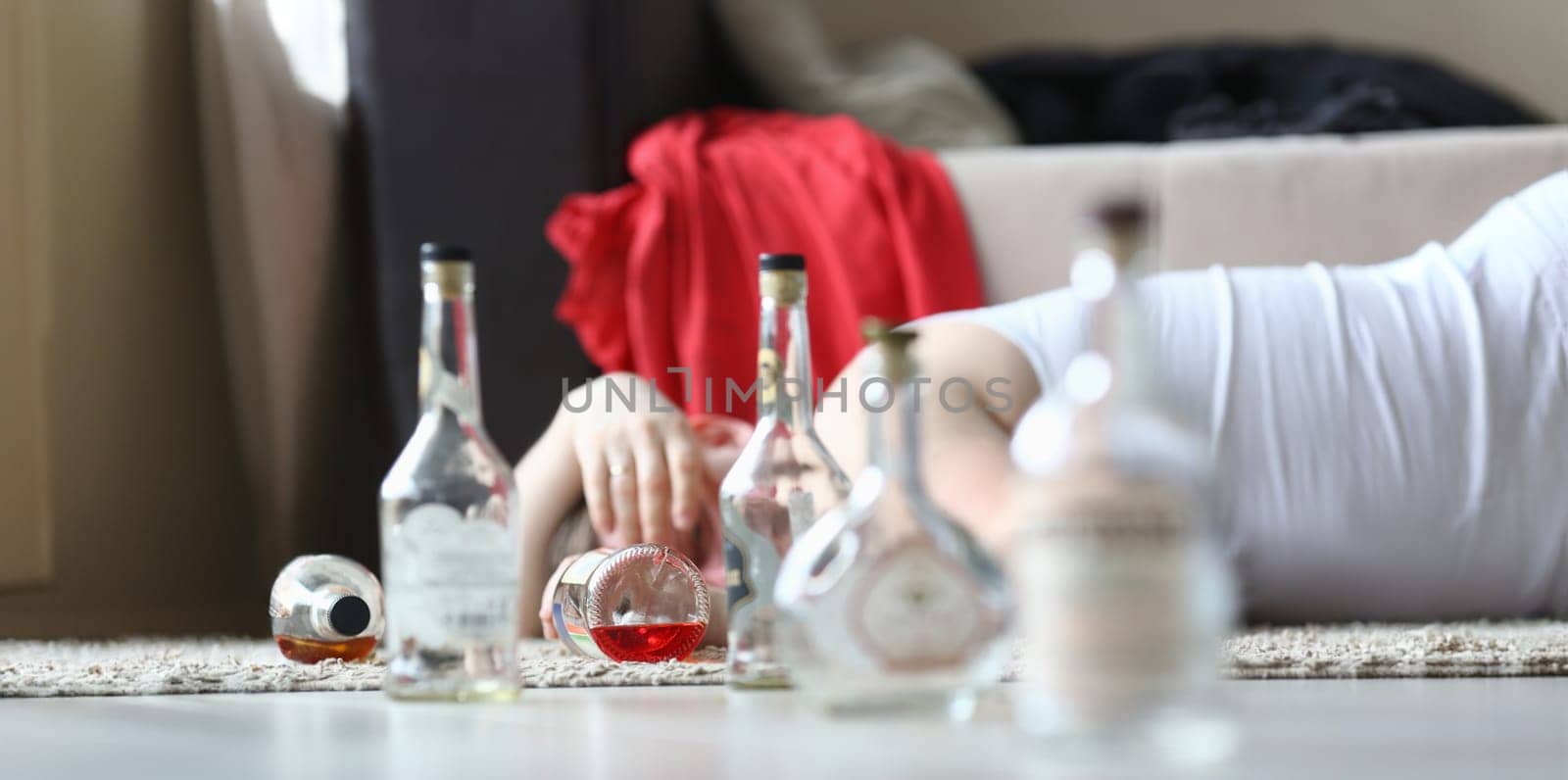 Portrait of male napping after rough night party. Male drunkard sleeping on comfortable sofa and holding bottle of expensive alcohol. Consequences of irresponsible drinking concept