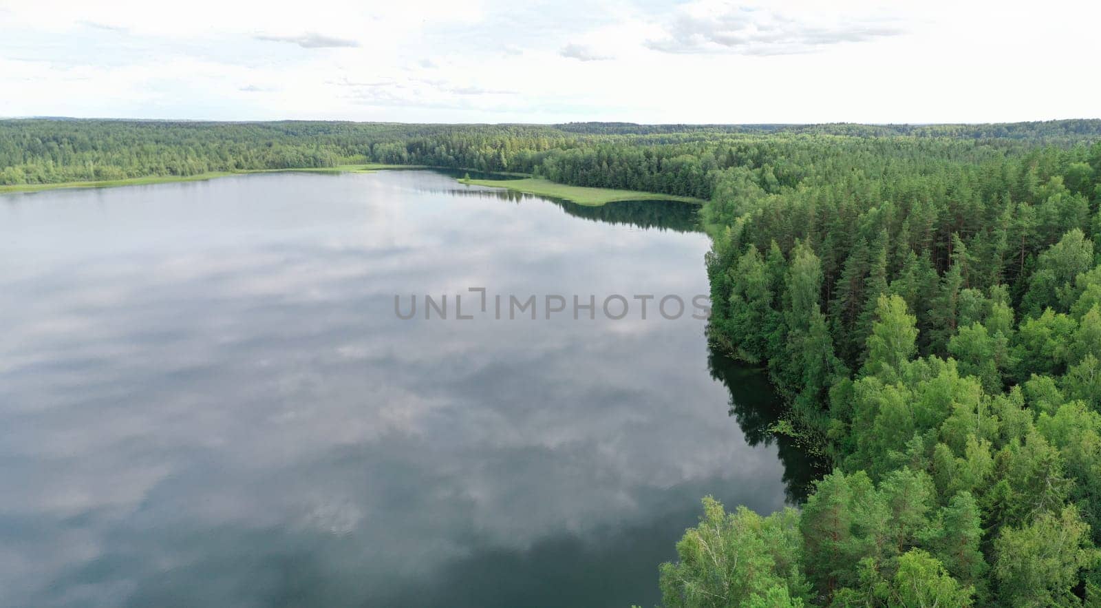 Topview of wood and riverside. Horizon dividing cloudy sky and green wild nature. Landscape of valley with trees and water with reflection on summer time