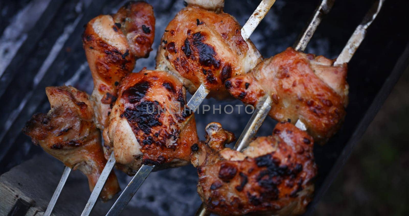 Close-up of grilling tasty dish on barbecue. Process of cooking yummy shashlik in nature. Delicious food on metal skewer in bbq. Time to picnic concept
