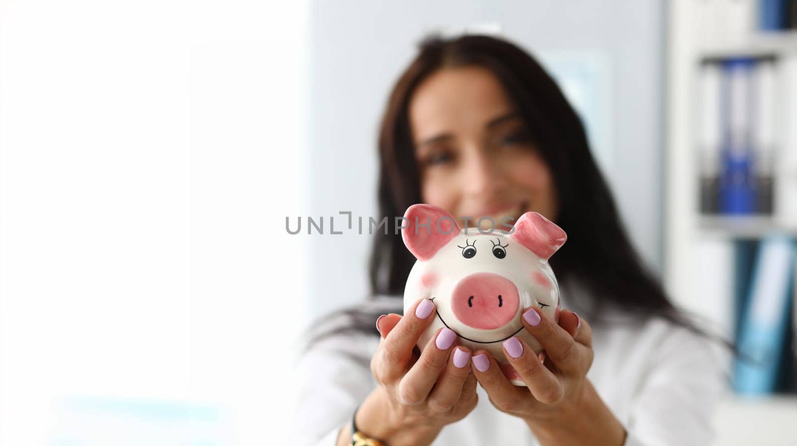 Focus on tender hands of smart businesswoman standing in modern office showing white ceramic figure with calmness and happiness. Pretty female wearing shirt. Small change money store concept