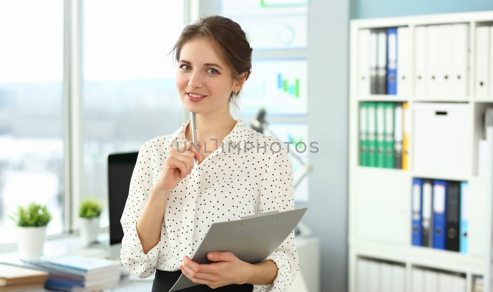 Portrait of personable smiling woman in meeting room. Businesswoman posing in modern office and looking at camera with gladness. Company concept. Blurred background