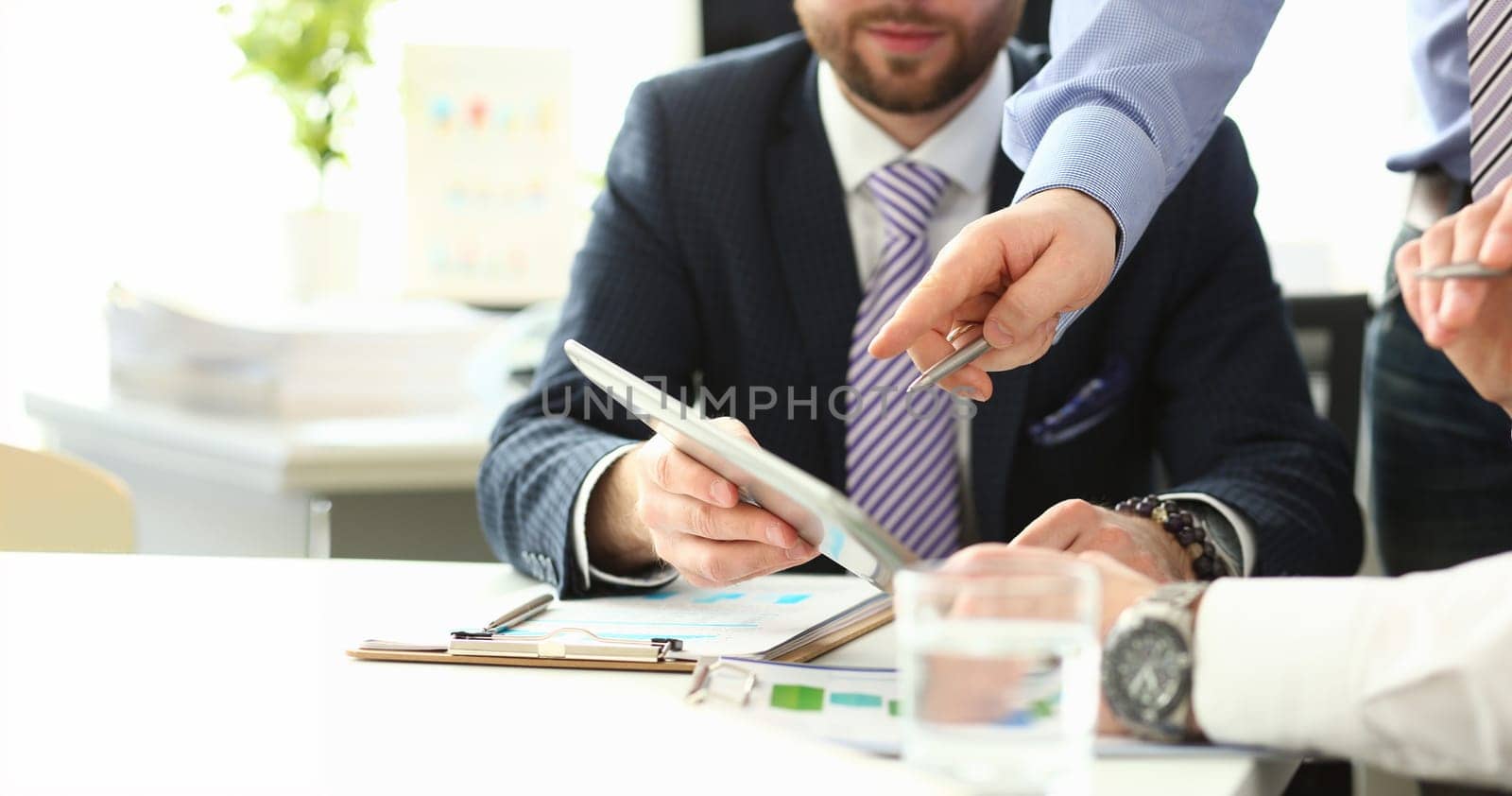 Close-up of smart colleagues working in big modern office and talking about complicated agreement. Young manager explaining boss details hard to understand. Company meeting concept