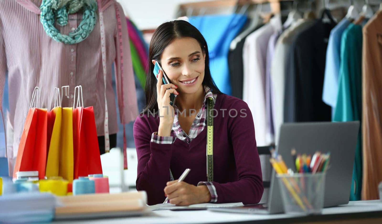 Portrait of pretty business person looking at screen of computer. Smart business lady talking on smartphone and looking away with gladness. Fashioner concept