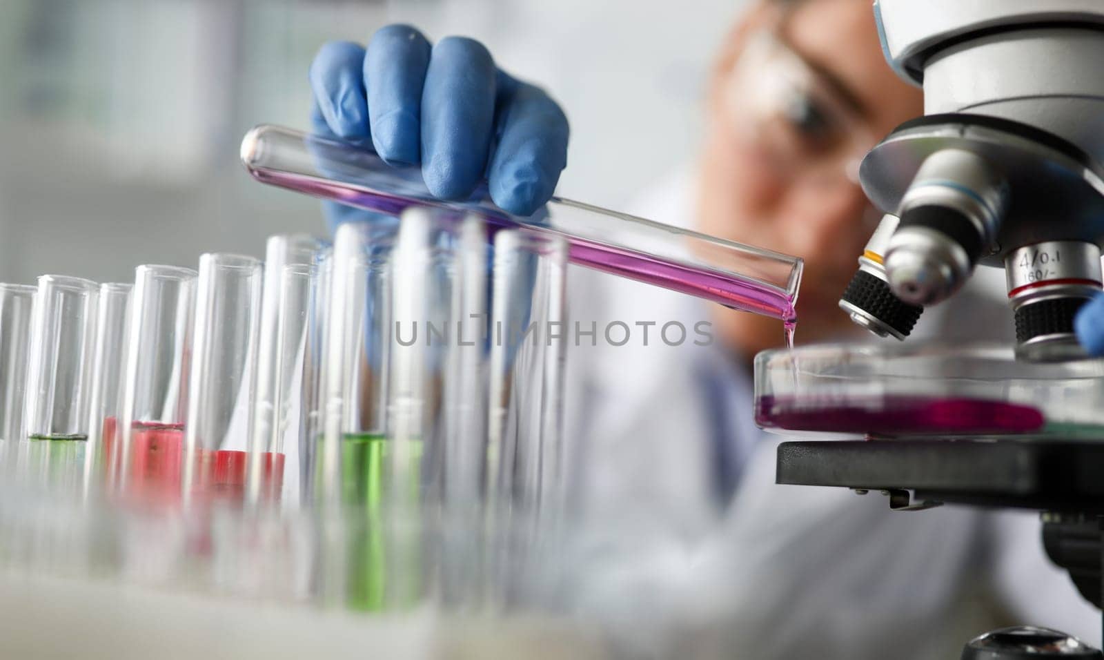 Female chemist holds test tube of glass in hand closeup overflows liquid solution potassium permanganate. Conducts an analysis reaction takes various versions reagents using chemical manufacturing