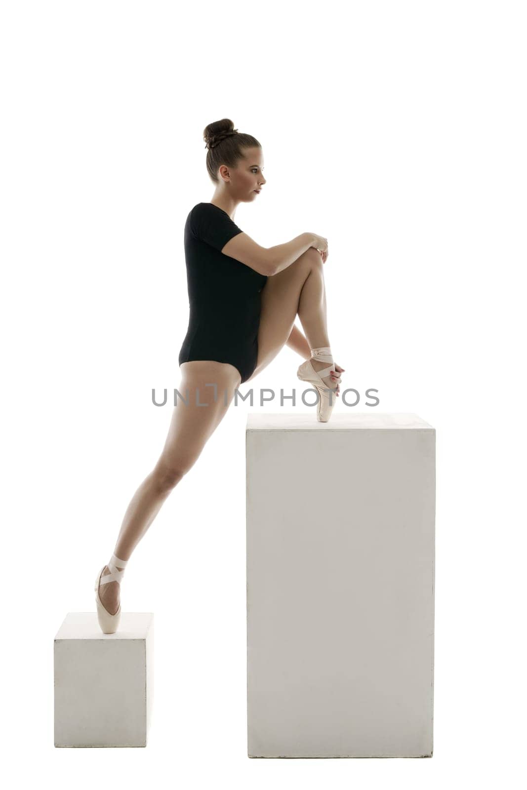 Ballerina doing stretching exercises in studio, isolated on white