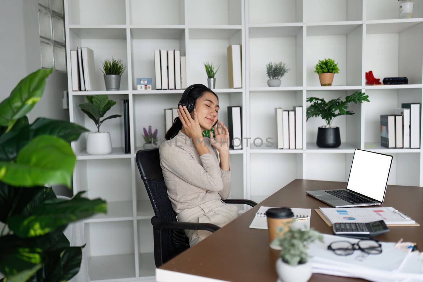 business woman employee wear headphone, listen to music to relax while working, white blank screen by itchaznong