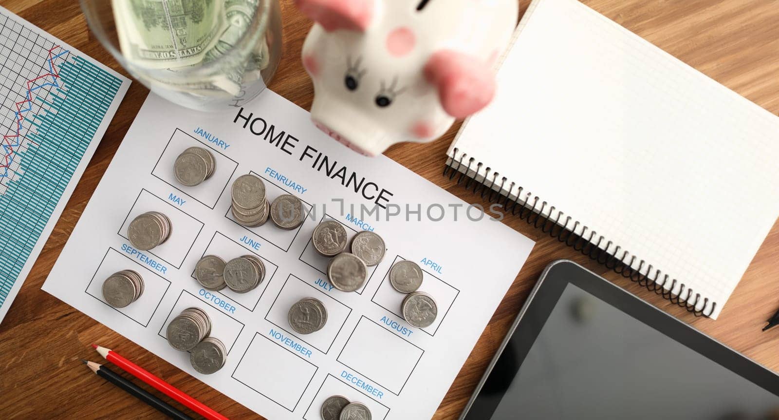 Top view of coin tover with paper calendar against wooden table background. Home finance concept