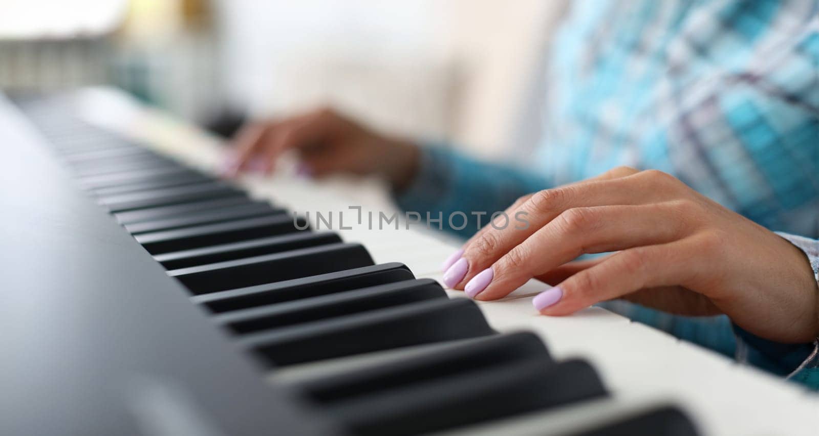 Close-up of female hands playing synthesizer in music workshop. Professional cute pianist creating new musical composition. Art concept. Blurred background