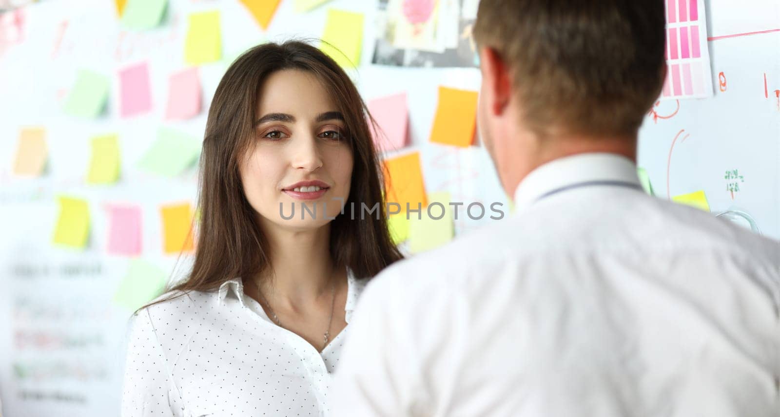 Pretty female office worker consulting her male coworker by kuprevich