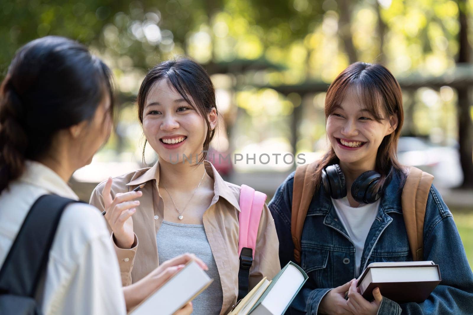 Happy students walking together on university campus, chatting and laughing outdoors after classes.