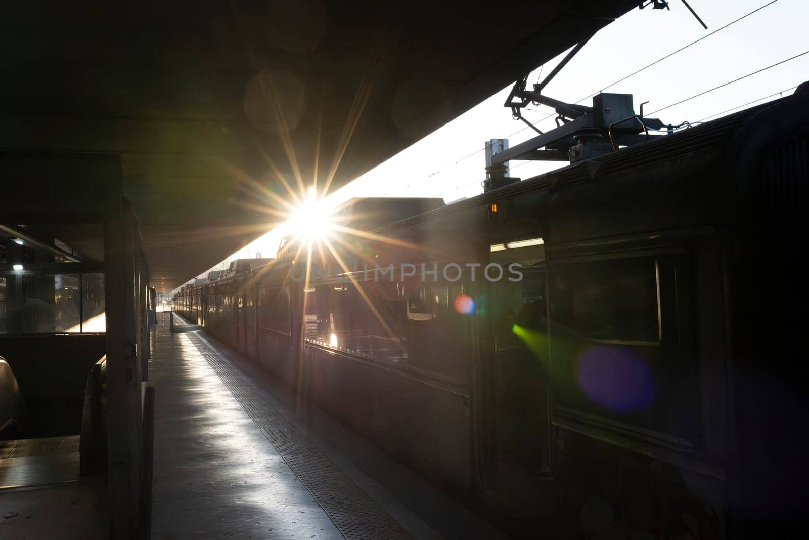 A train is on the tracks with the sun shining on it, sunset