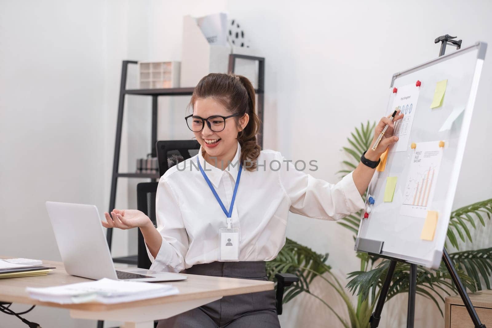 A beautiful female company employee is presenting her work or marketing plan on a board through an online meeting..