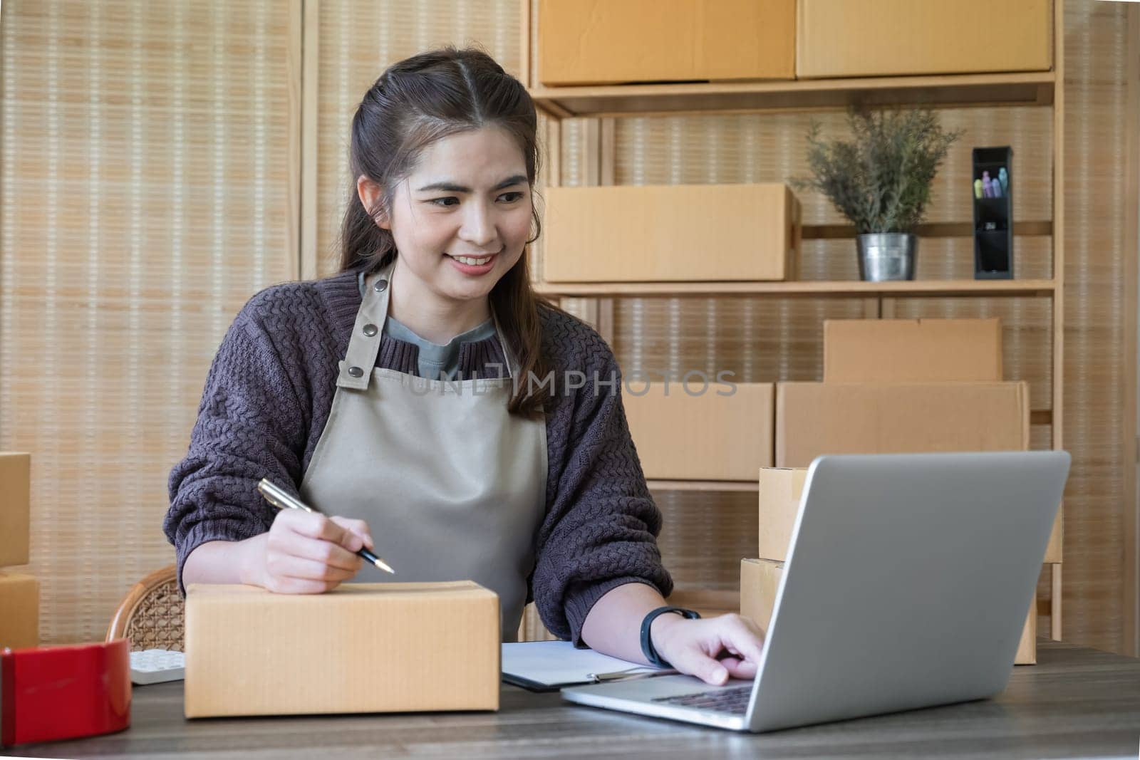 SME business entrepreneurs small in Asia Write shipping information on a cardboard box in home office. Small business operators preparing to ship to customer.