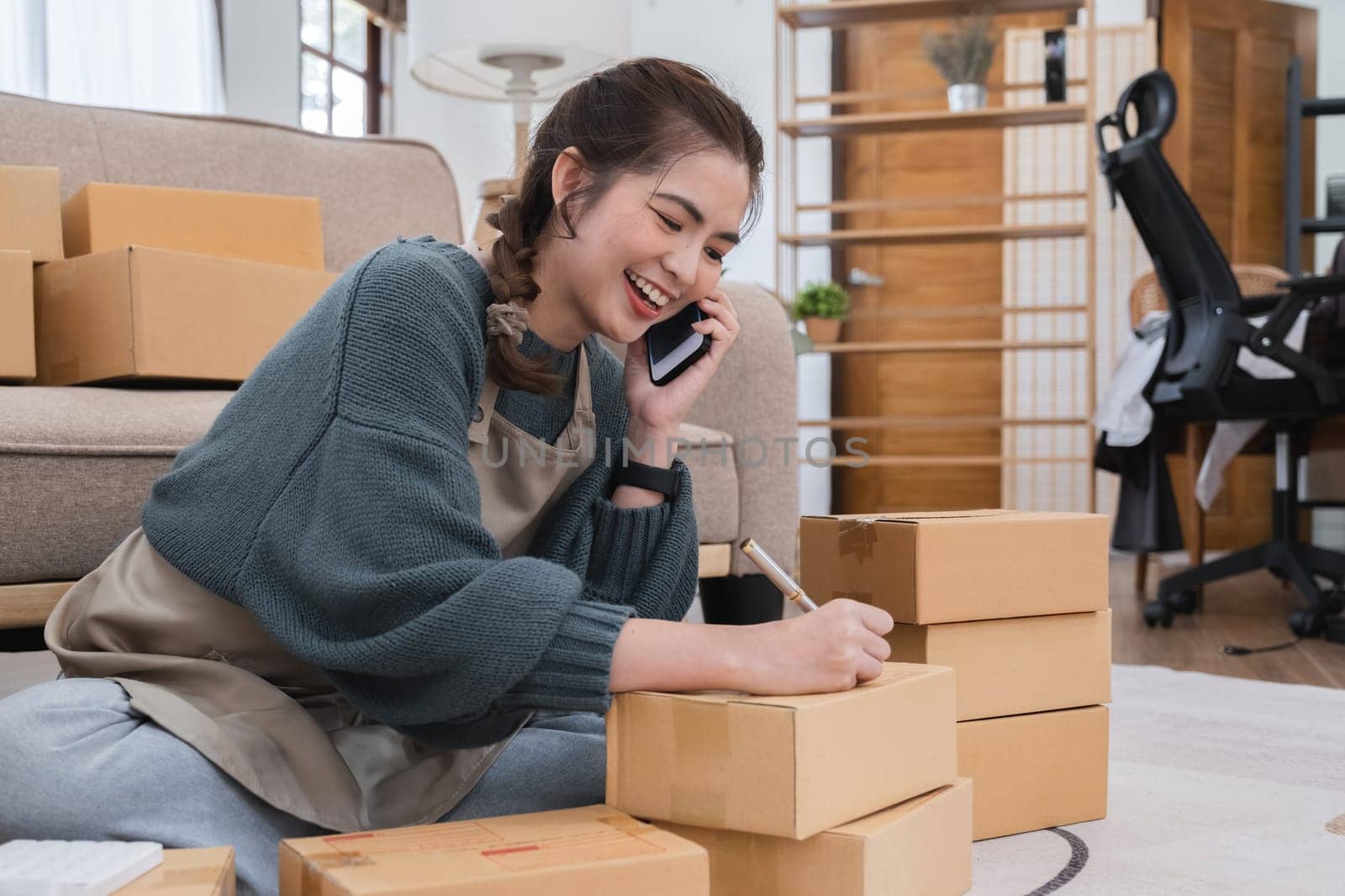 SME business entrepreneurs small in Asia Write shipping information on a cardboard box in home office. Small business operators preparing to ship to customer.