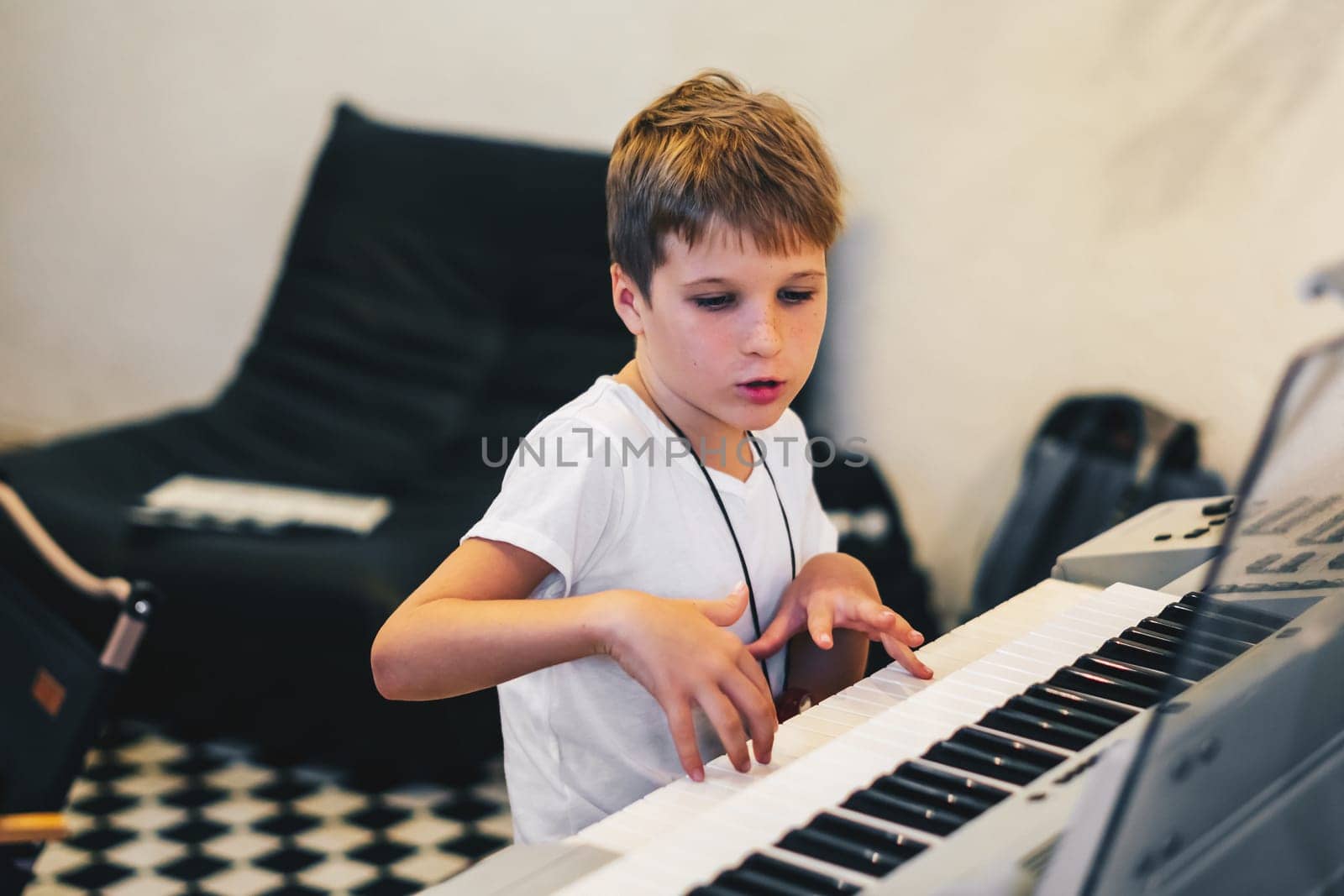 Young boy Portrait sitting at digital piano Playing keyboard focused kid activity indoors press on Key learning to play music room Hobby.