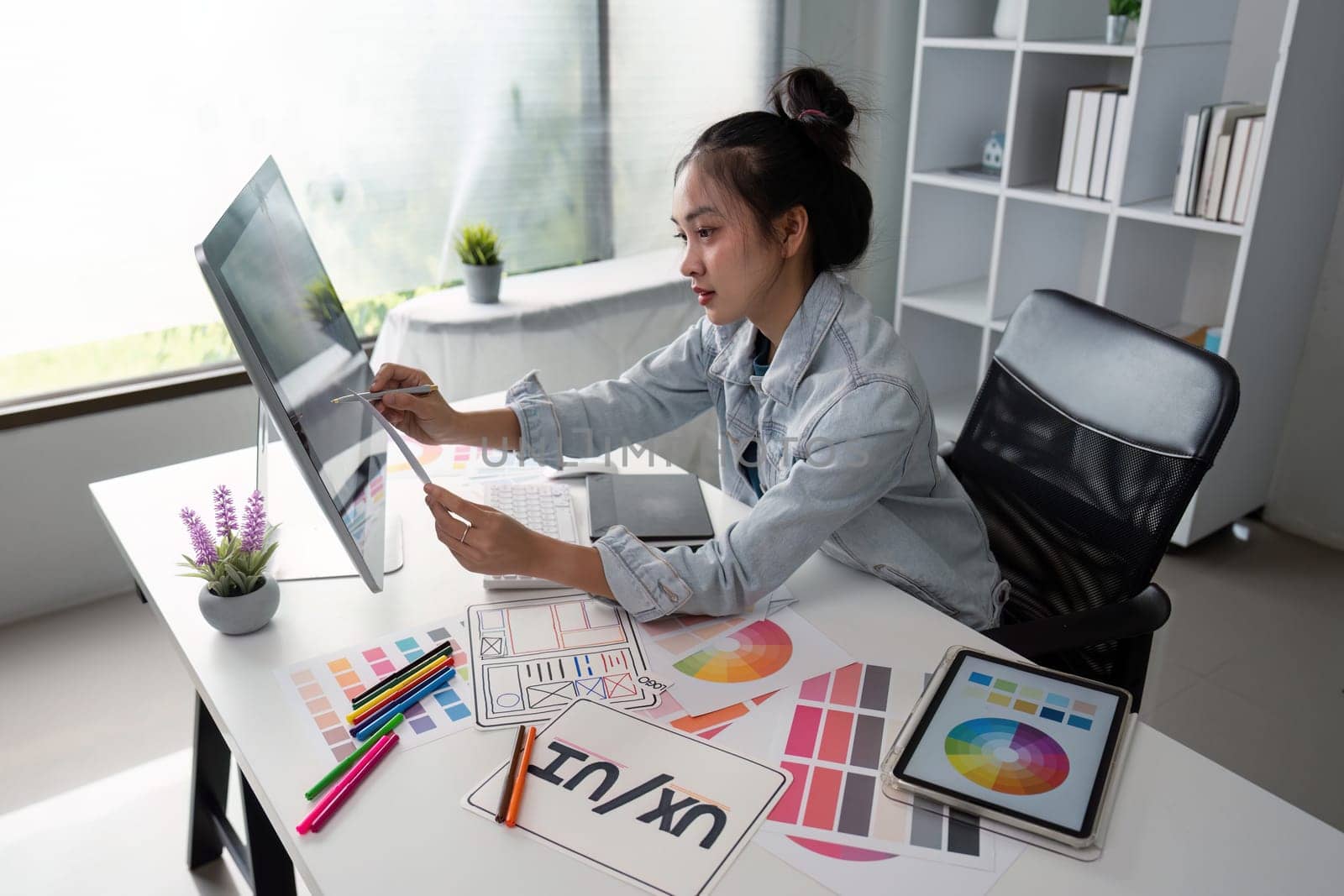 UX designer. Work on creative applications. Man with a palette in his hands. Designer applies the primary colors to the monitors. Development of a training application. Designer is a freelancer by nateemee