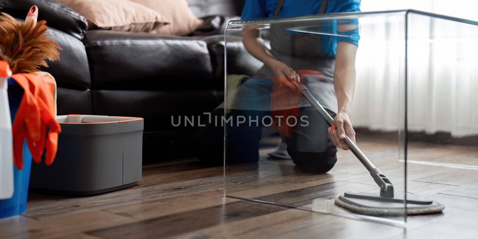 Asian cleaning service woman worker cleaning in living room at home. Beautiful young girl housekeeper cleaner wear apron and wipe messy dirty floor for housekeeping housework in house by nateemee