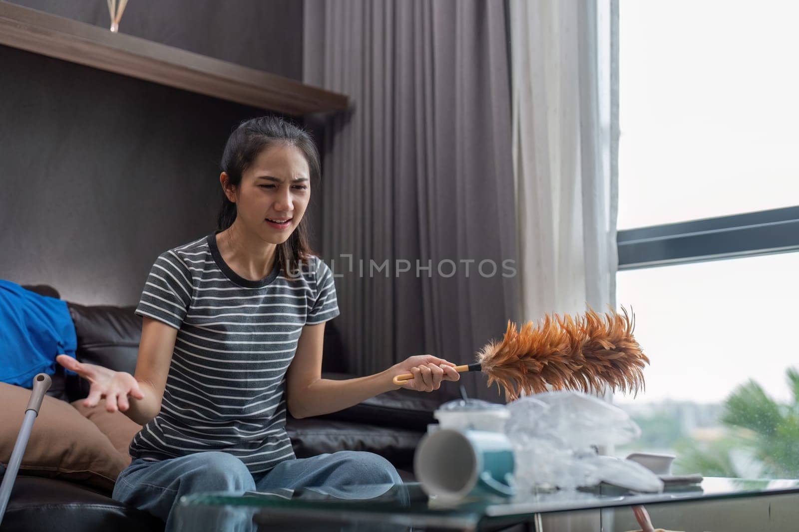 Tired young woman asian in the living room with cleaning products and equipment, housekeeper or overwhelmed girl with housework, stress cleaning, Housework concept by nateemee