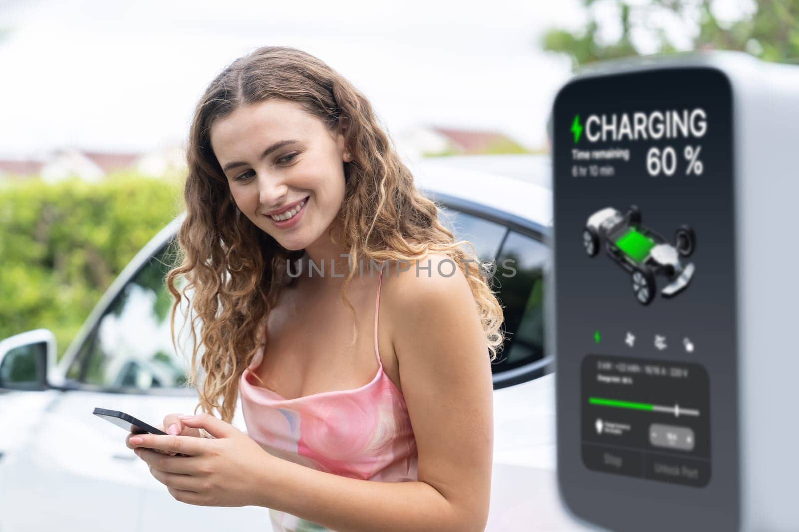 Modern eco woman recharge EV car with smartphone. Synchronos by biancoblue