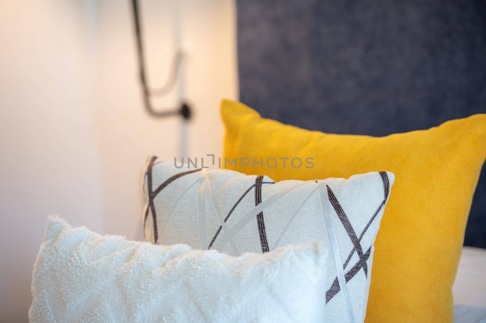 Colorful cushions on bed in illuminated room.