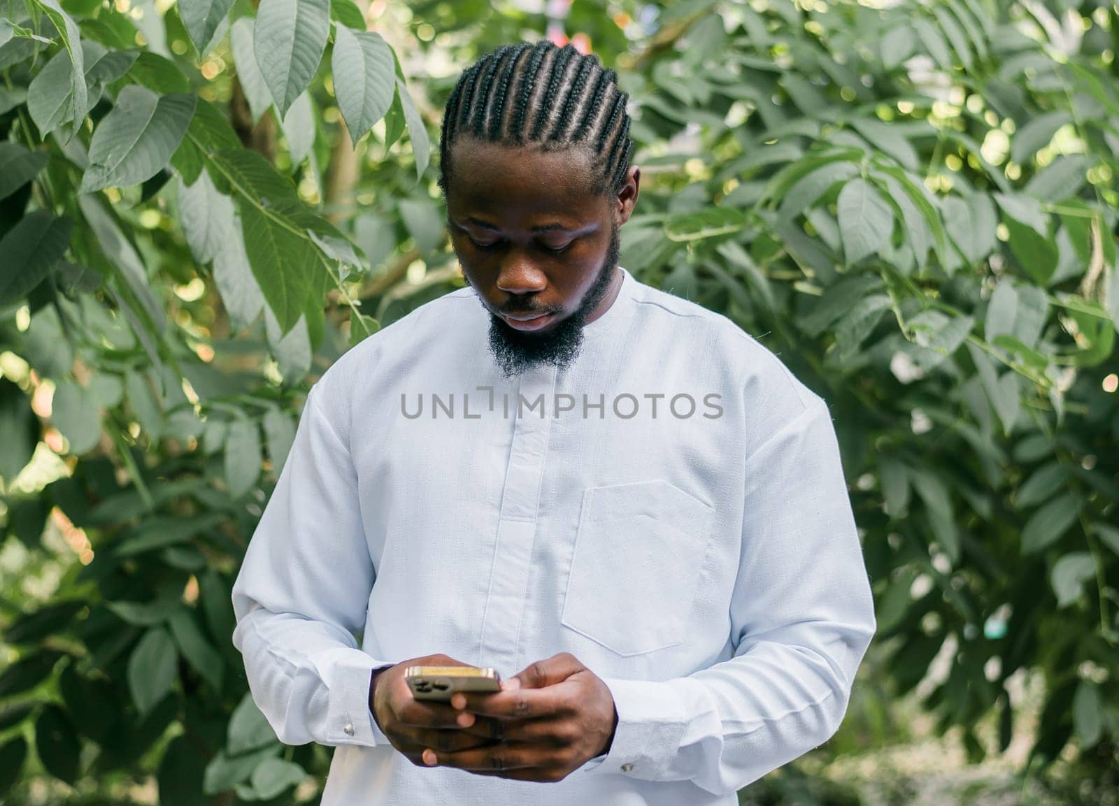 Millennial generation african american man typing sms outdoor 5g internet concept. High speed internet on phone and chatting on social networks and blog