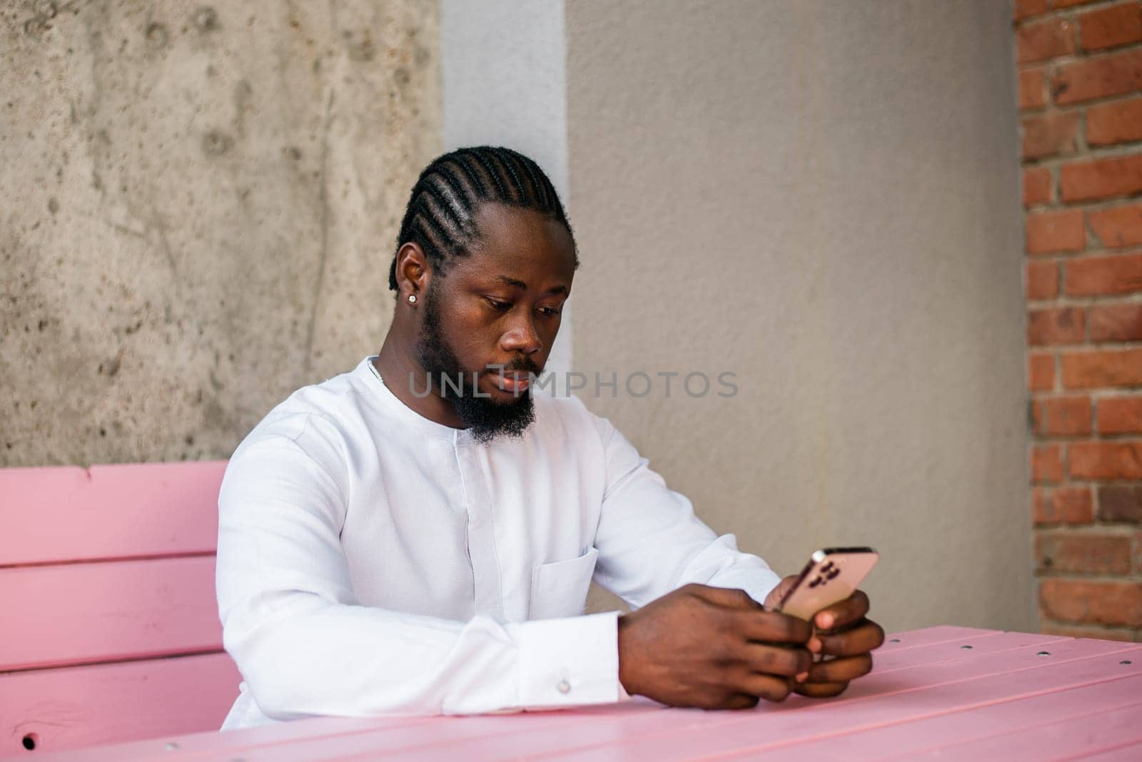 Millennial generation african american man typing sms outdoor 5g internet concept. High speed internet on phone and chatting on social networks and blog