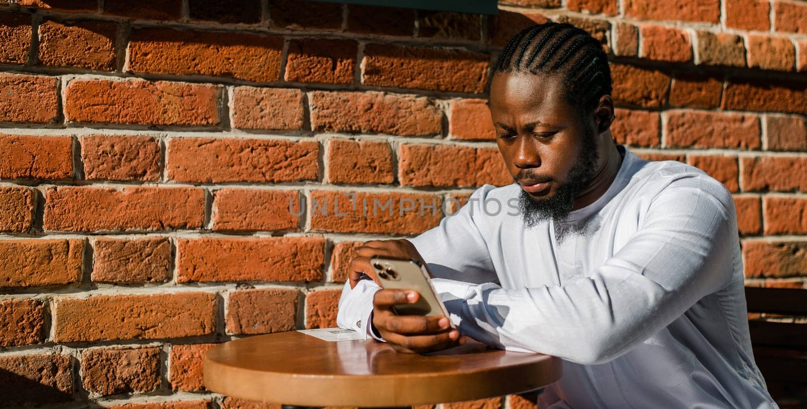 Millennial generation african american man typing sms outdoor 5g internet concept. High speed internet on phone and chatting on social networks and blog