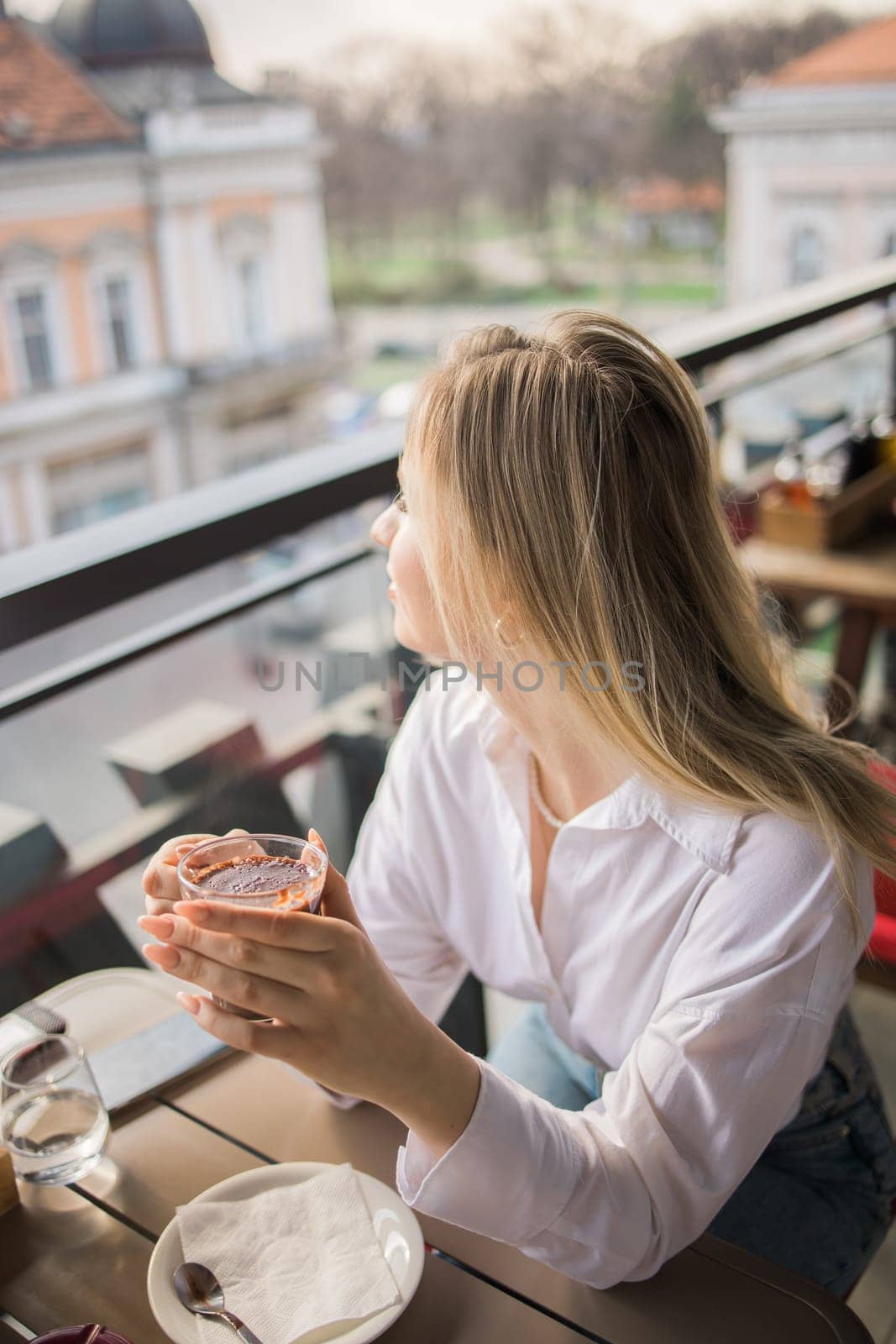 Gen z blonde woman drinks hot chocolate in summer cafe. Tasty beverage and break