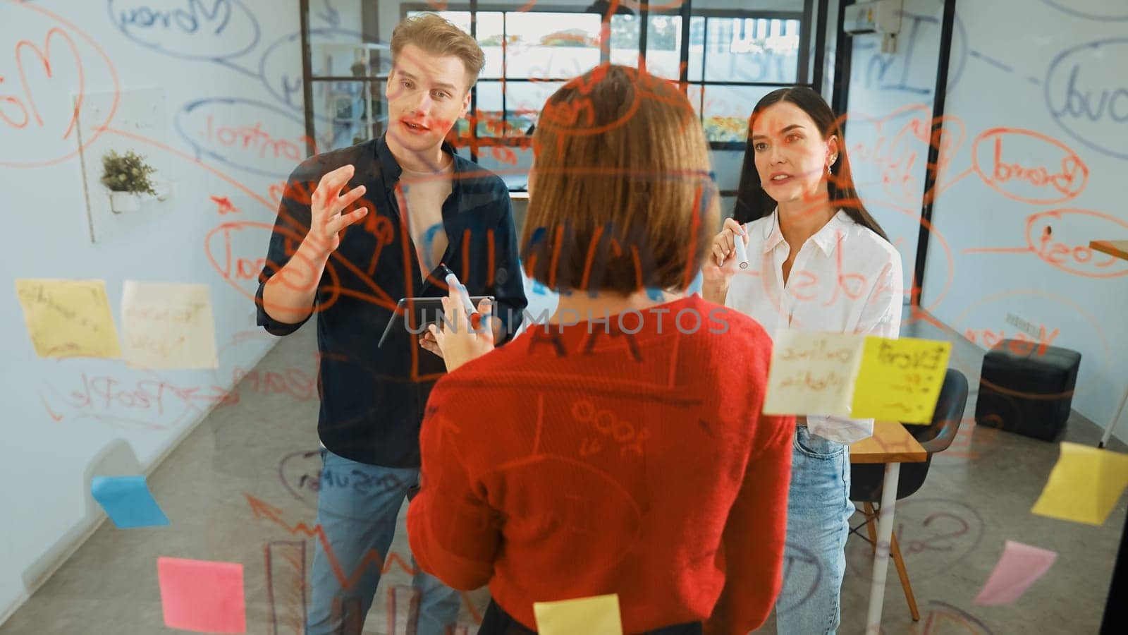 Creative start up team brainstorming marketing idea while cooperative caucasian businesswoman presents creative solution in front of glass board at business meeting. Working together. Immaculate.
