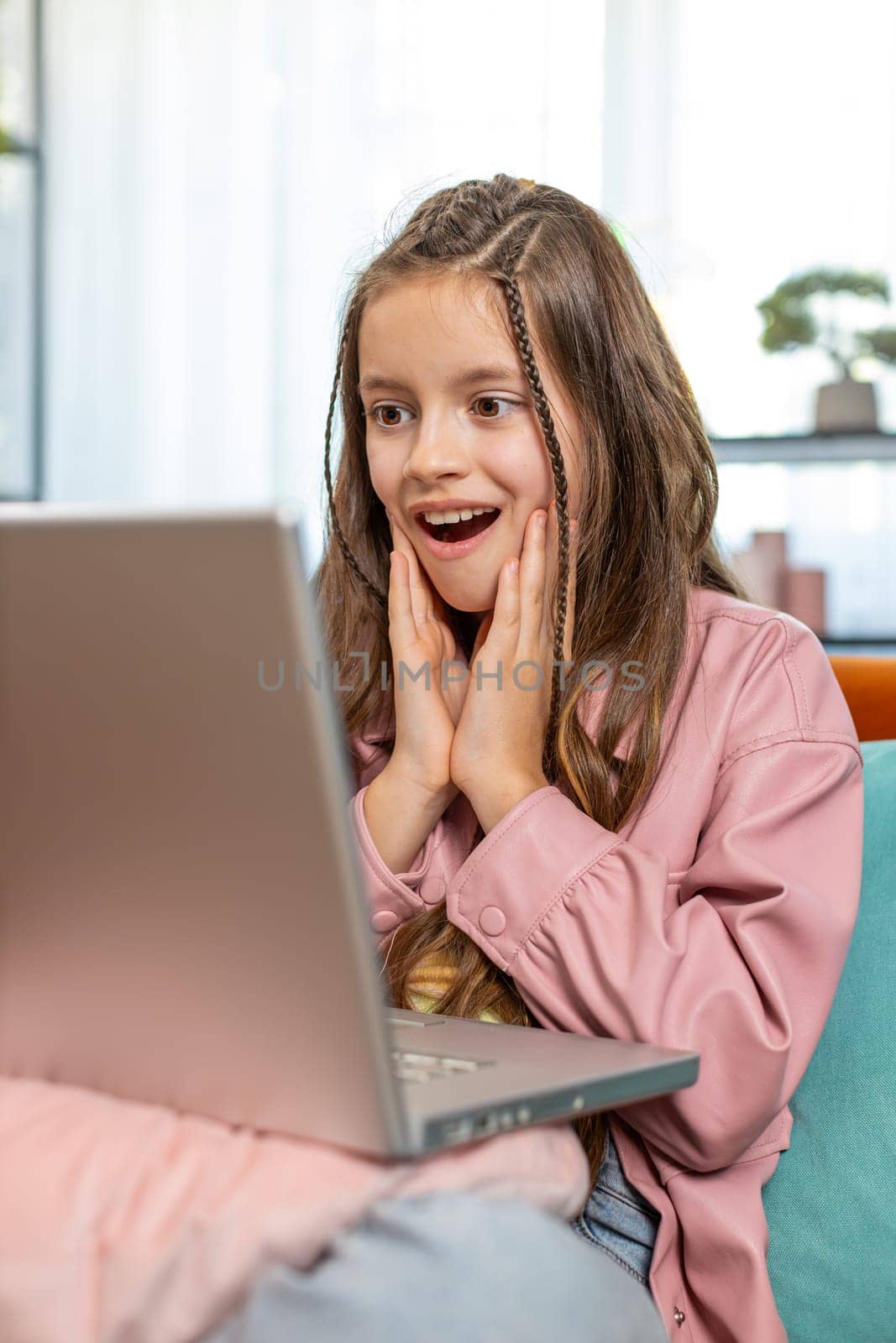 Surprised happy girl child using laptop computer, receive good news message, shocked by sudden victory celebrate lottery game jackpot win purchases online shopping at home. Lifestyle technologies.