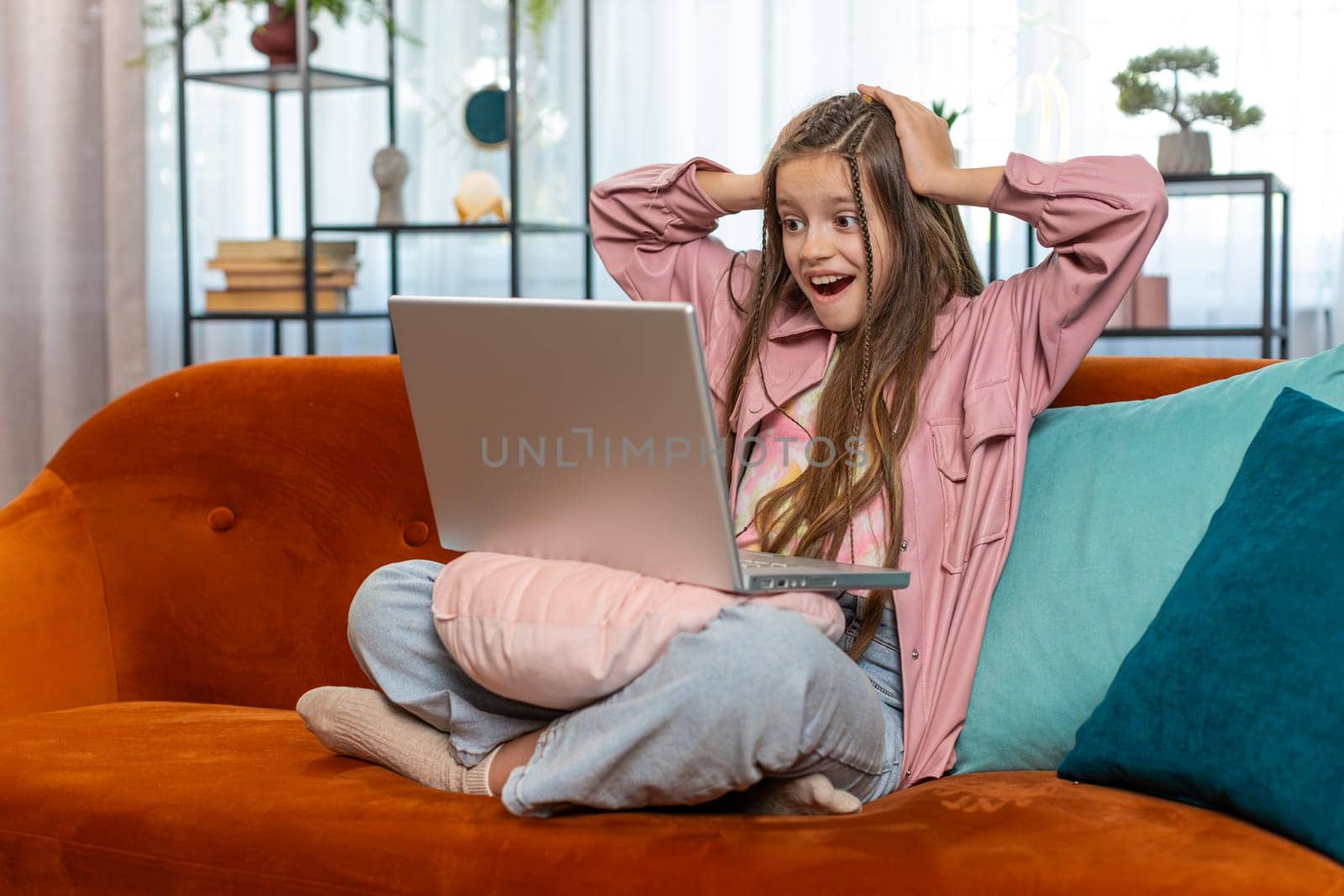 Surprised happy girl child using laptop computer, receive good news message, shocked by sudden victory celebrate lottery game jackpot win purchases online shopping at home. Lifestyle technologies.