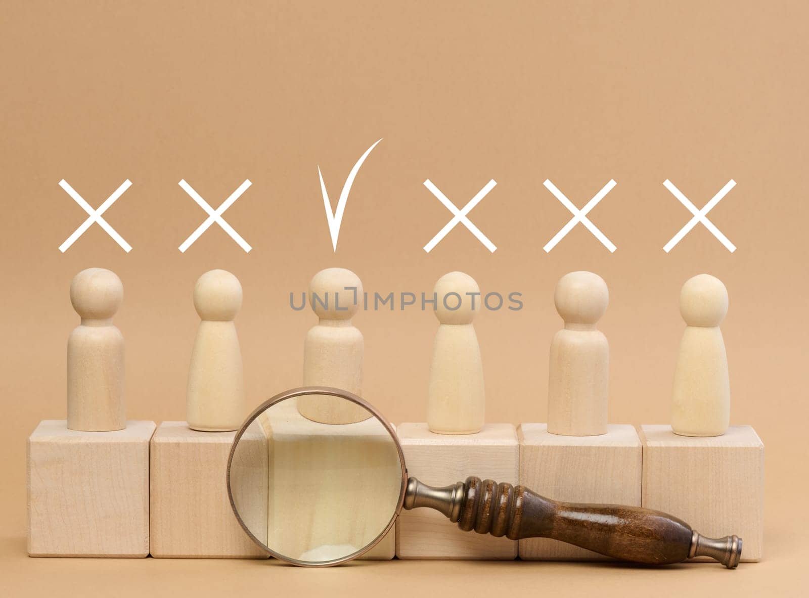 Wooden figures of men stand on a beige background and a wooden magnifying glass. Recruitment concept, search for talented and capable employees, career growth