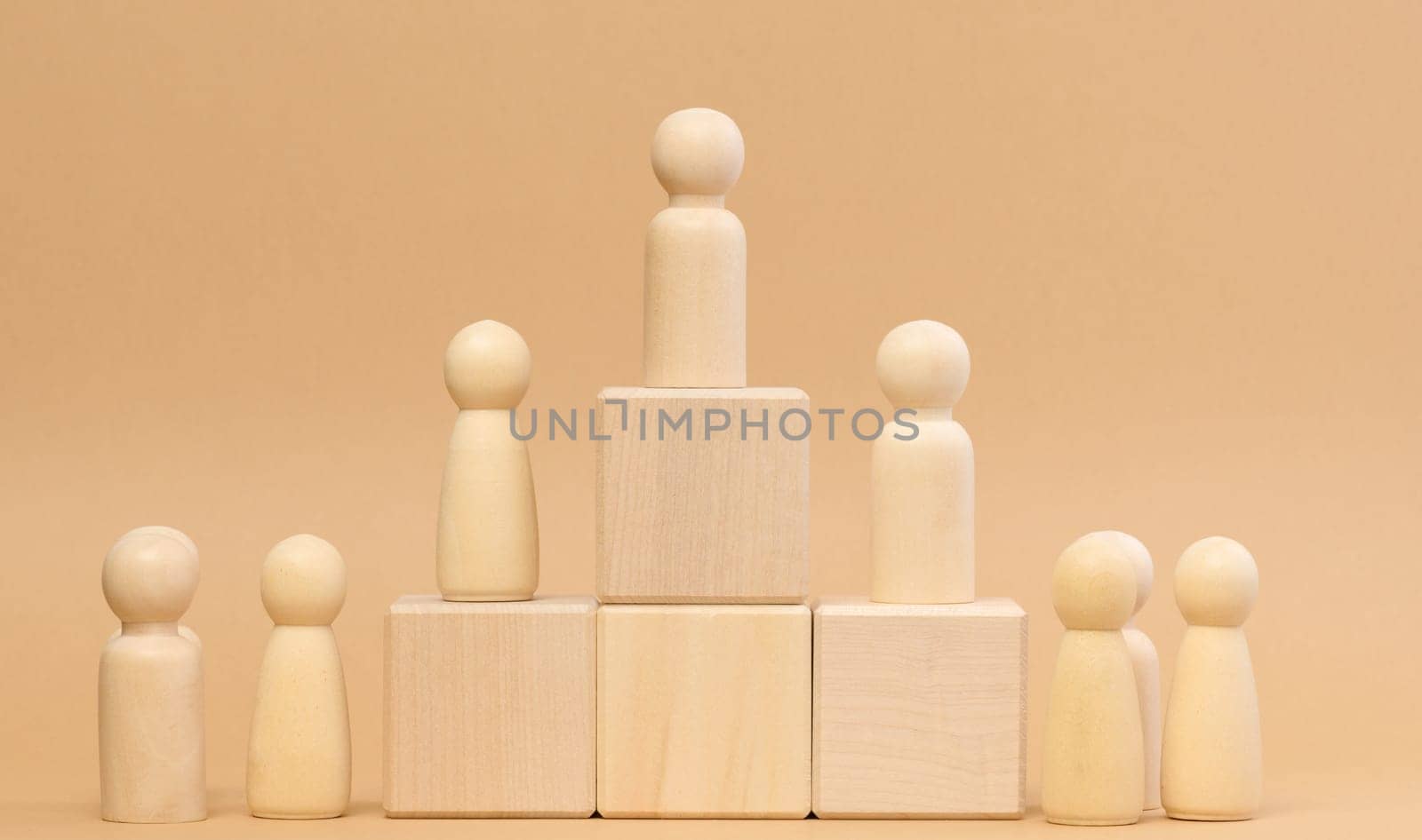 Wooden figures of men stand on a pedestal. The concept of rivalry in sports, business and life. Achieving success and leadership