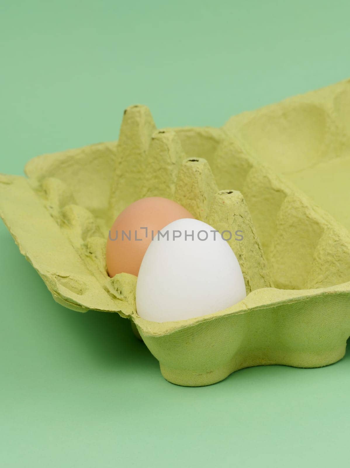 Two chicken eggs in a paper box on a green background by ndanko