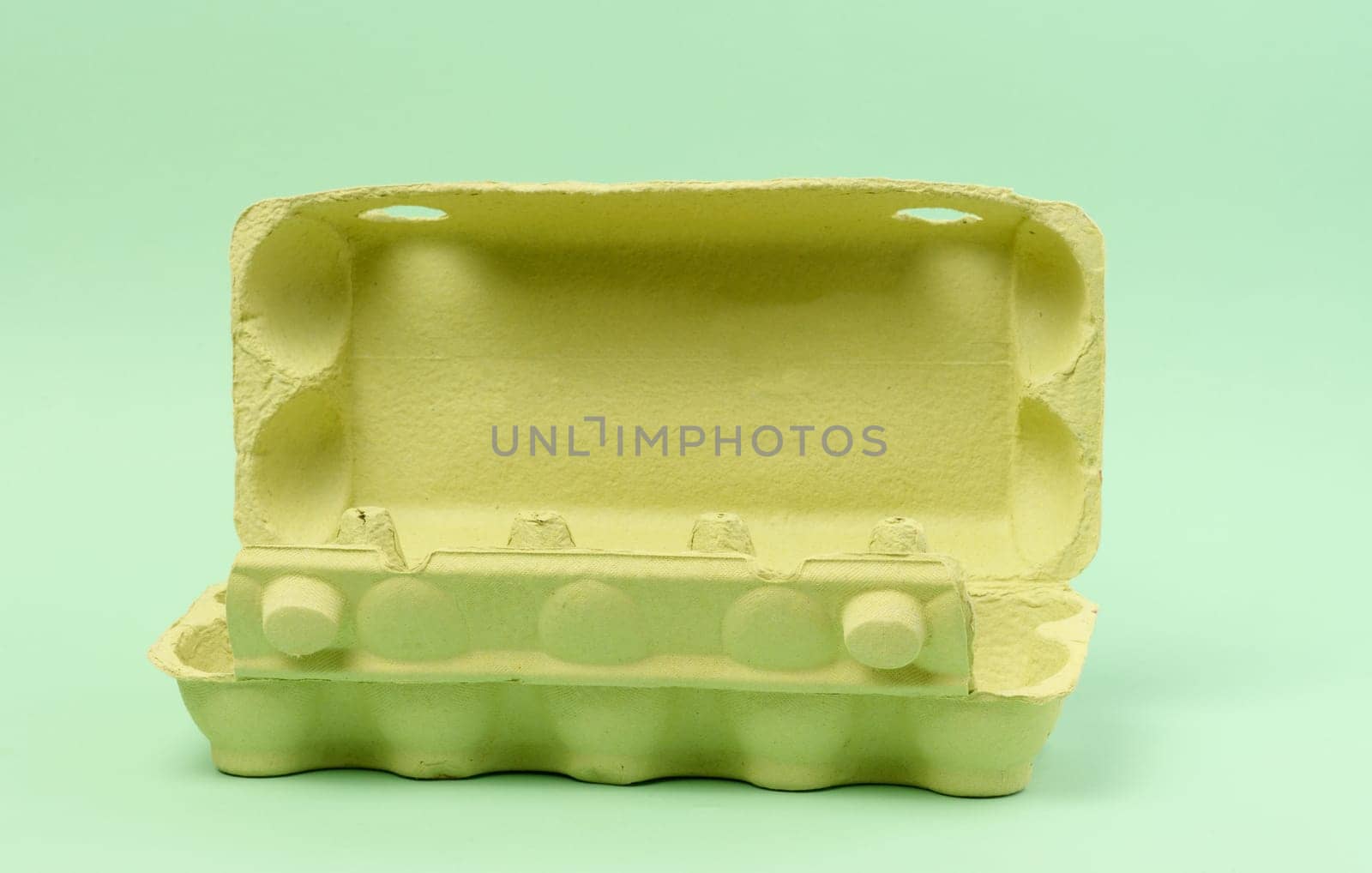 Open green recycled egg carton box on green background, storage